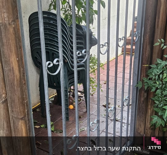 שער מתכת עם עיטורים, ליד כיסאות פלסטיק ירוקים